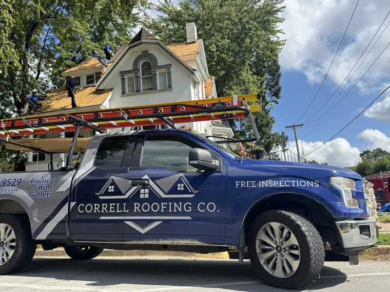Correll Roofing F-150 with a ladder rack at an older two-story house while the crew tears off the roof