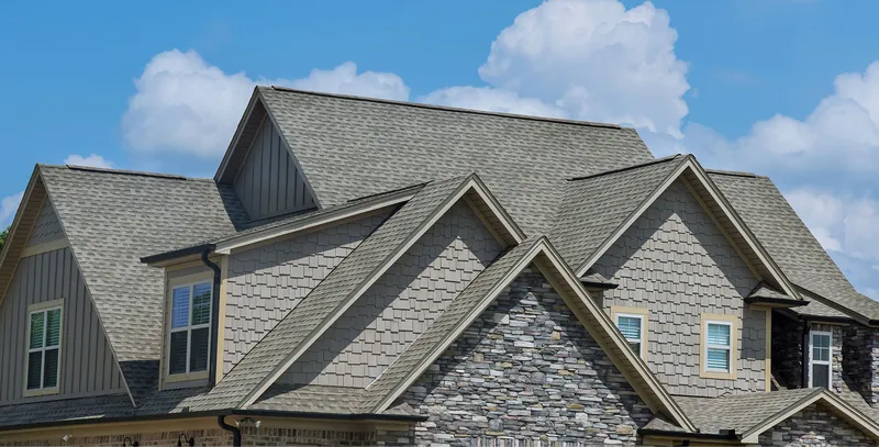 Two-story home with gray architectural shingles, gables and stone accents