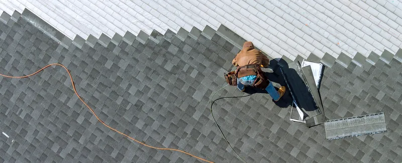 Roofer nailing shingles, seen from above