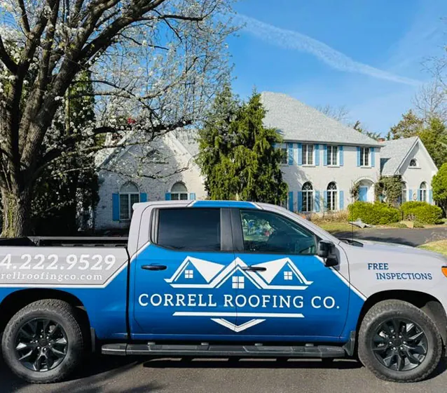 Correll Roofing Co. pickup with Free Inspections on the door, parked in front of a large white home